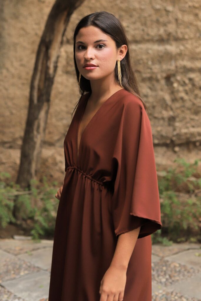 Vestido midi marrón con escote pico y tejido fluido. Ideal para eventos y ocasiones especiales con un estilo elegante.