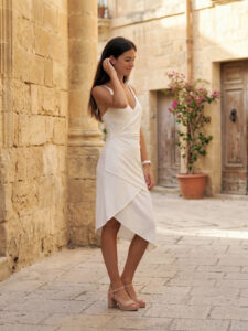 Vestido blanco de tirantes con escote cruzado y falda midi con volantes. Fresco, femenino y perfecto para eventos de día o novia civil.
