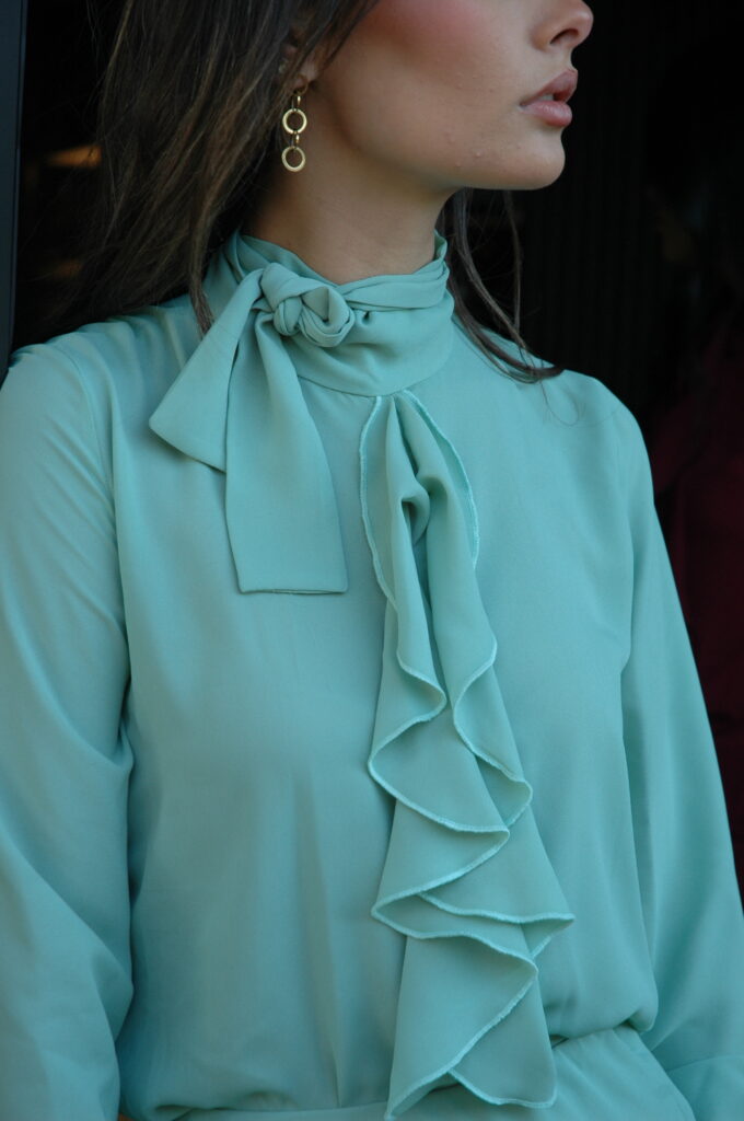 Blusa verde con volantes María. Diseño elegante con lazo al cuello y volantes frontales. Ideal para oficina, eventos o looks sofisticados.