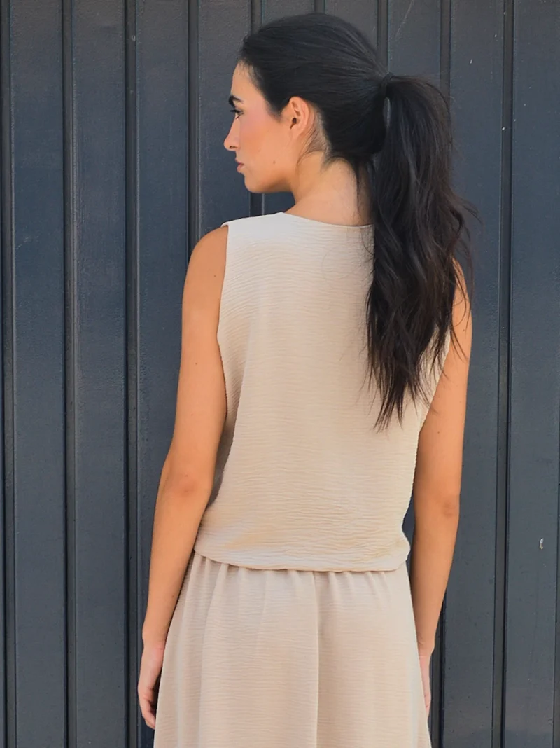Chaleco beige arena sin mangas con solapas clásicas y bolsillos delanteros. Diseño elegante y versátil ideal para looks de oficina y estilismos casual chic.