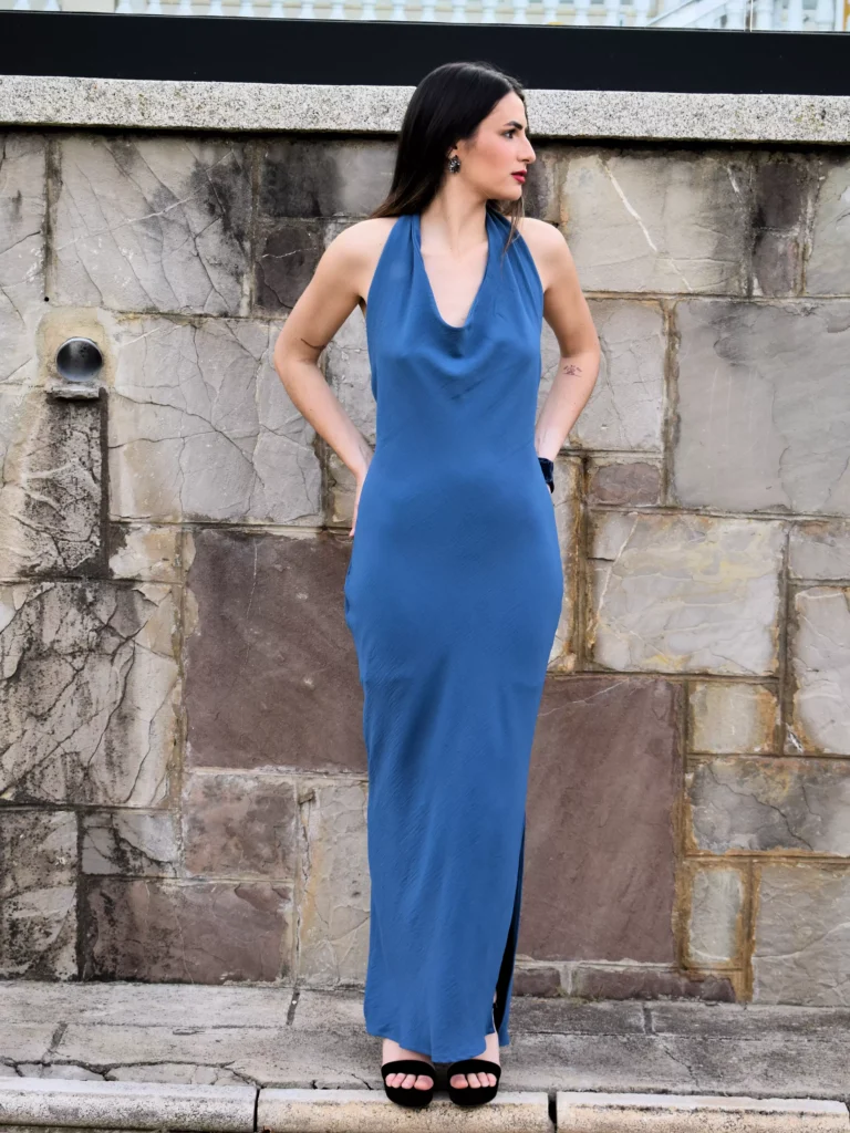 Su silueta ajustada en punto de alta caída realza la figura con naturalidad, mientras que su escote halter con drapeado tipo cascada aporta un toque sensual