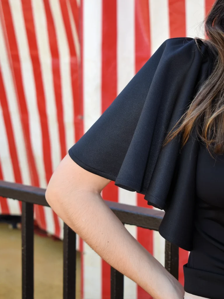 Blusa negra con volantes en los hombros y corte entallado en tejido elástico. Diseño elegante y versátil ideal para eventos, oficina y looks de noche.