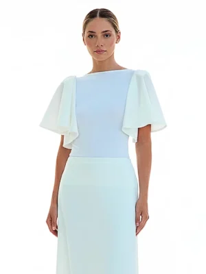 Blusa blanca con volantes y cuello barco en punto de seda. Diseño elegante y fluido ideal para invitadas, eventos de día y looks sofisticados.