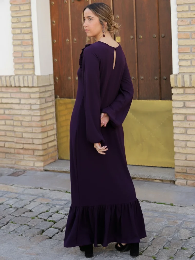 Vestido Largo Berenjena Palma con volantes, tejido fluido y mangas abullonadas. Elegante y favorecedor, ideal para eventos y celebraciones.