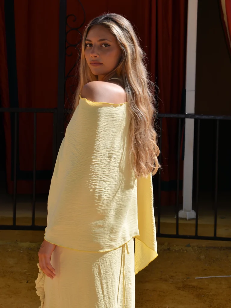 Vestido largo amarillo con capa y espalda descubierta: un diseño luminoso y elegante para invitadas de día y celebraciones.