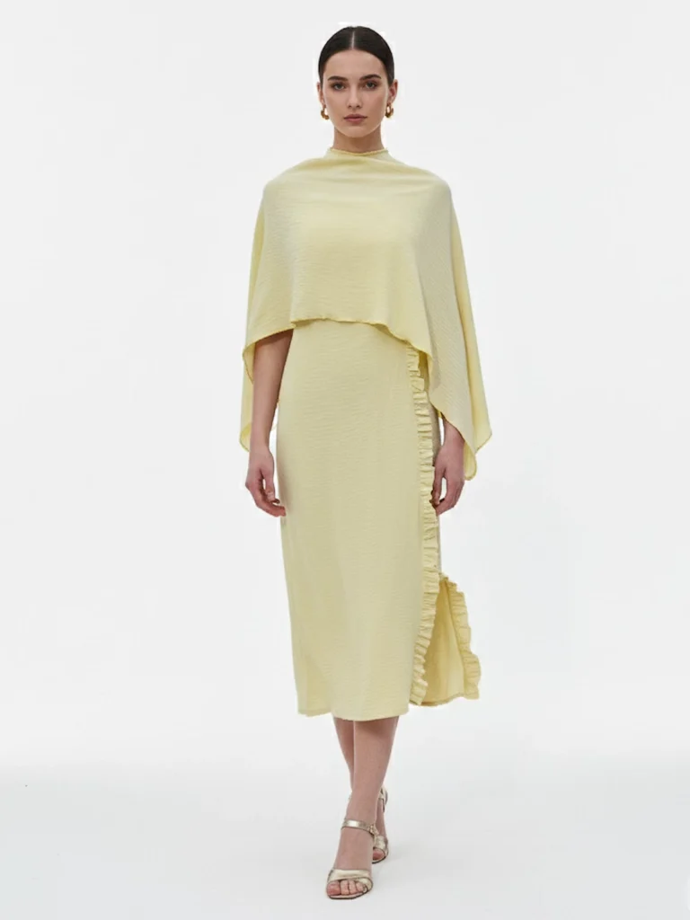 Vestido largo amarillo con capa y espalda descubierta: un diseño luminoso y elegante para invitadas de día y celebraciones.