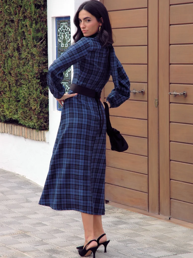 Vestido midi azul escocia de cuadros con cuello alto, mangas largas con volumen y fajín cinturón. Ideal para invitadas y eventos especiales.