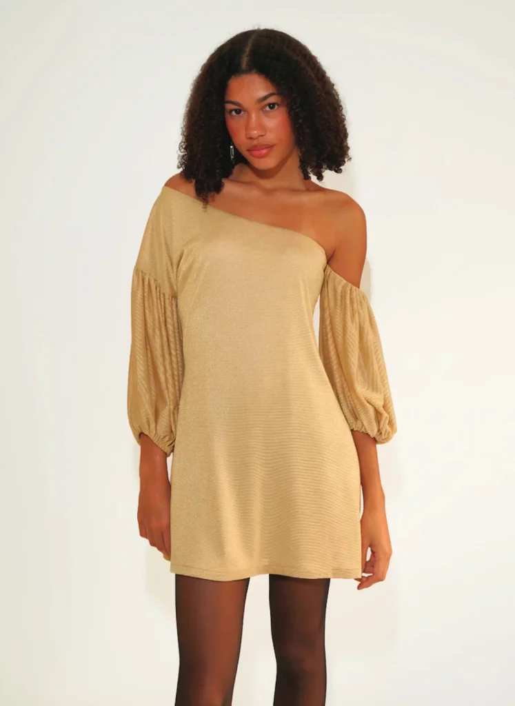 Vestido corto dorado asimétrico con manga abullonada y tejido fluido elástico. Diseño luminoso ideal para fiestas y eventos nocturnos.