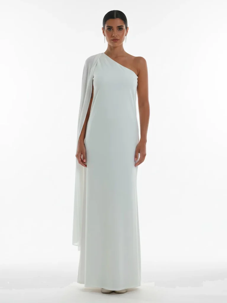 Vestido largo blanco con capa vaporosa y escote a un hombro. Ideal para bodas civiles y celebraciones elegantes.