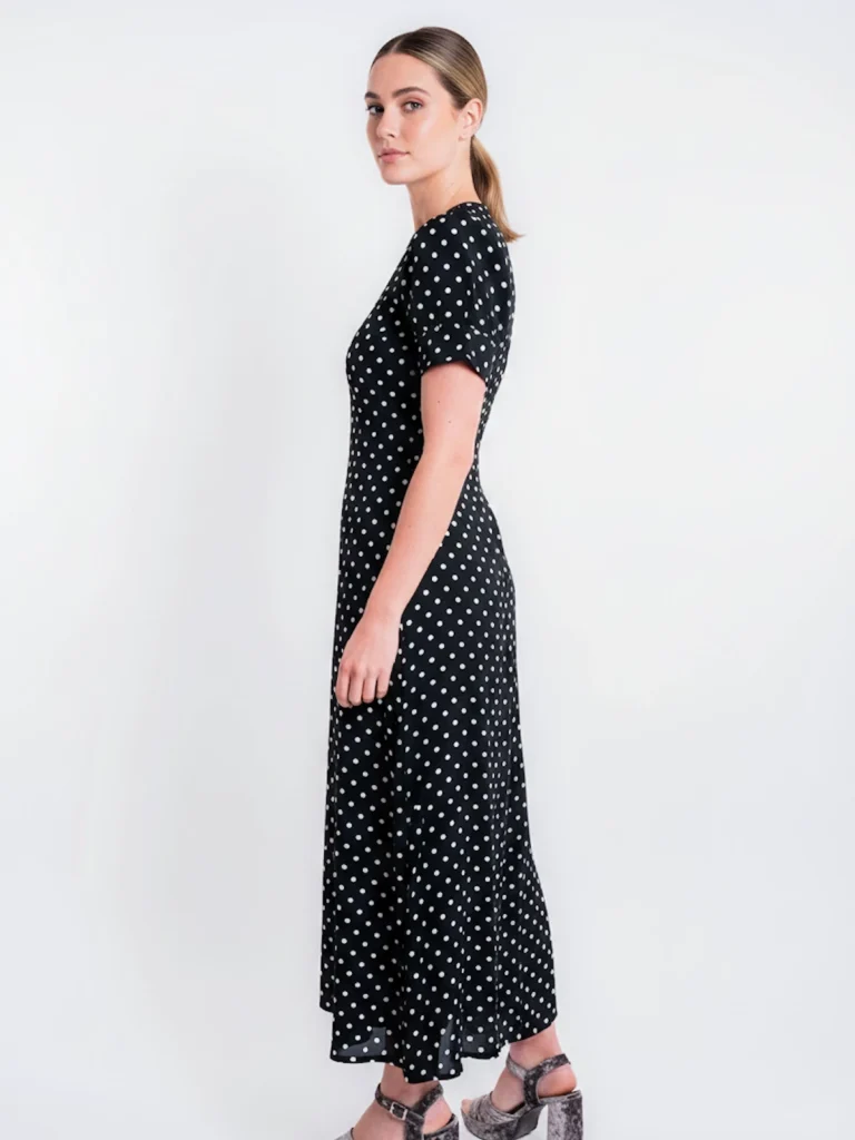 Vestido midi negro de lunares con manga corta y tejido fluido. Diseño atemporal ideal para oficina, eventos y looks diarios elegantes.