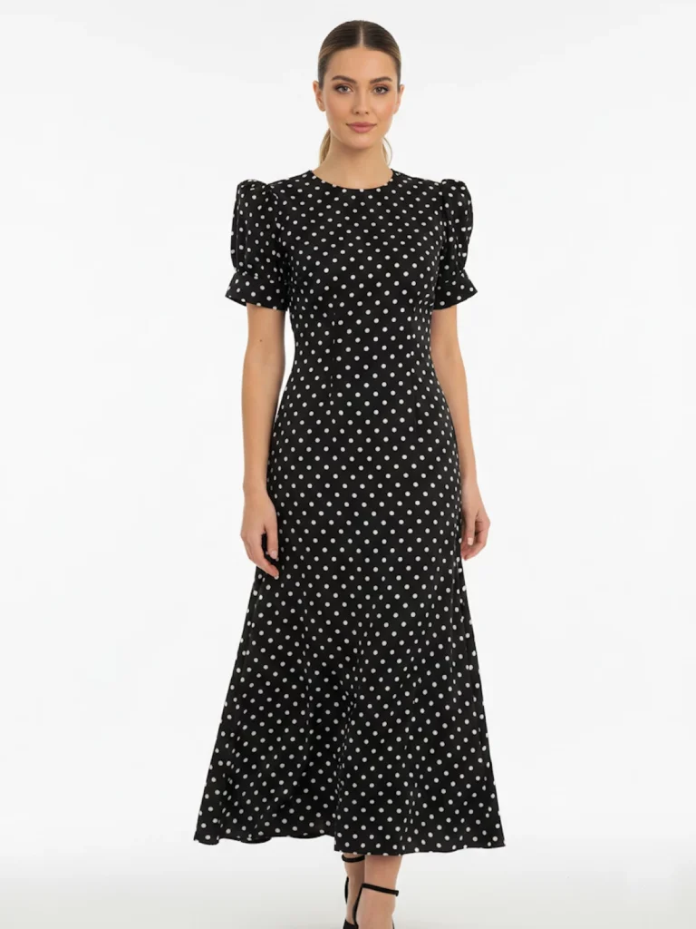 Vestido midi negro de lunares con manga corta y tejido fluido. Diseño atemporal ideal para oficina, eventos y looks diarios elegantes.
