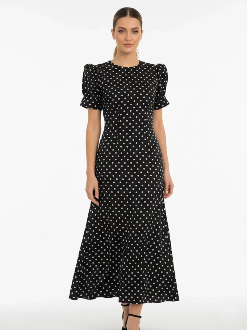 Vestido midi negro de lunares con manga corta y tejido fluido. Diseño atemporal ideal para oficina, eventos y looks diarios elegantes.