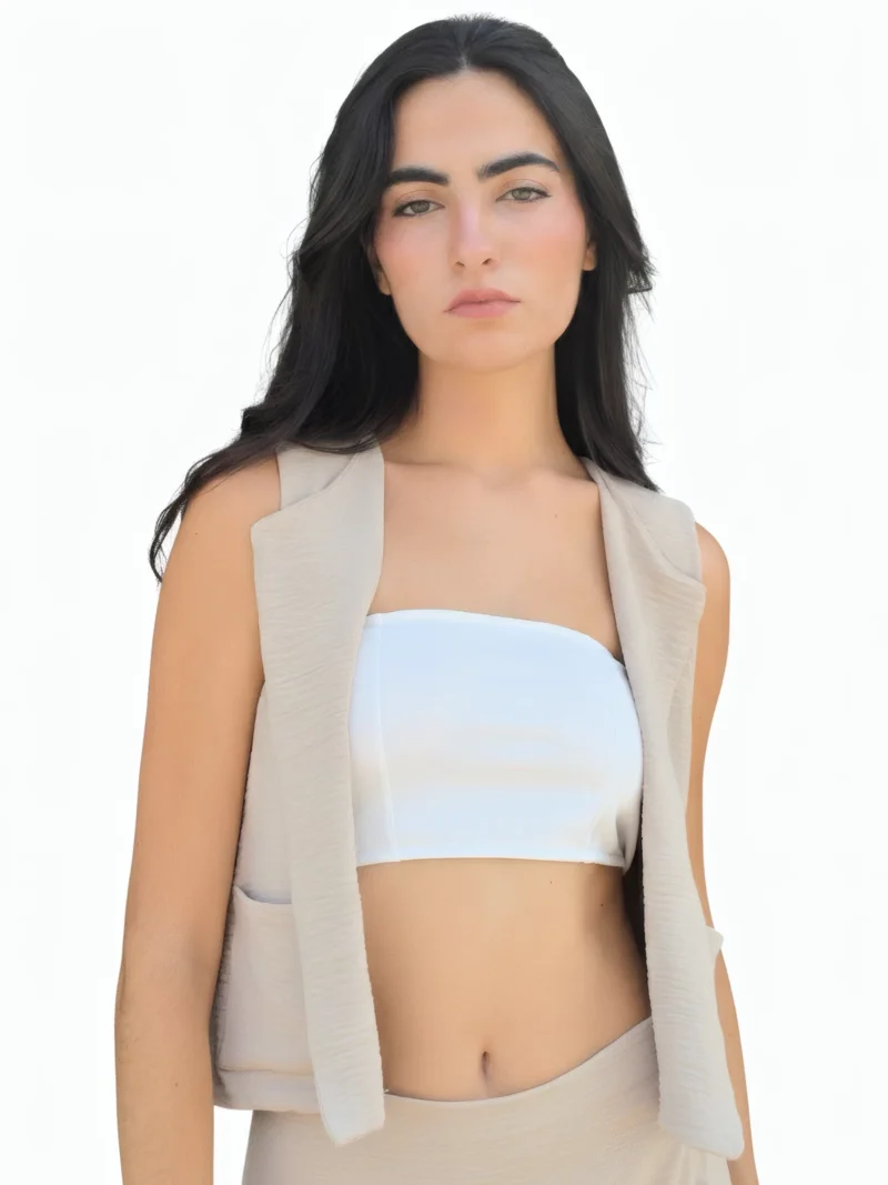 Chaleco beige arena sin mangas con solapas clásicas y bolsillos delanteros. Diseño elegante y versátil ideal para looks de oficina y estilismos casual chic.