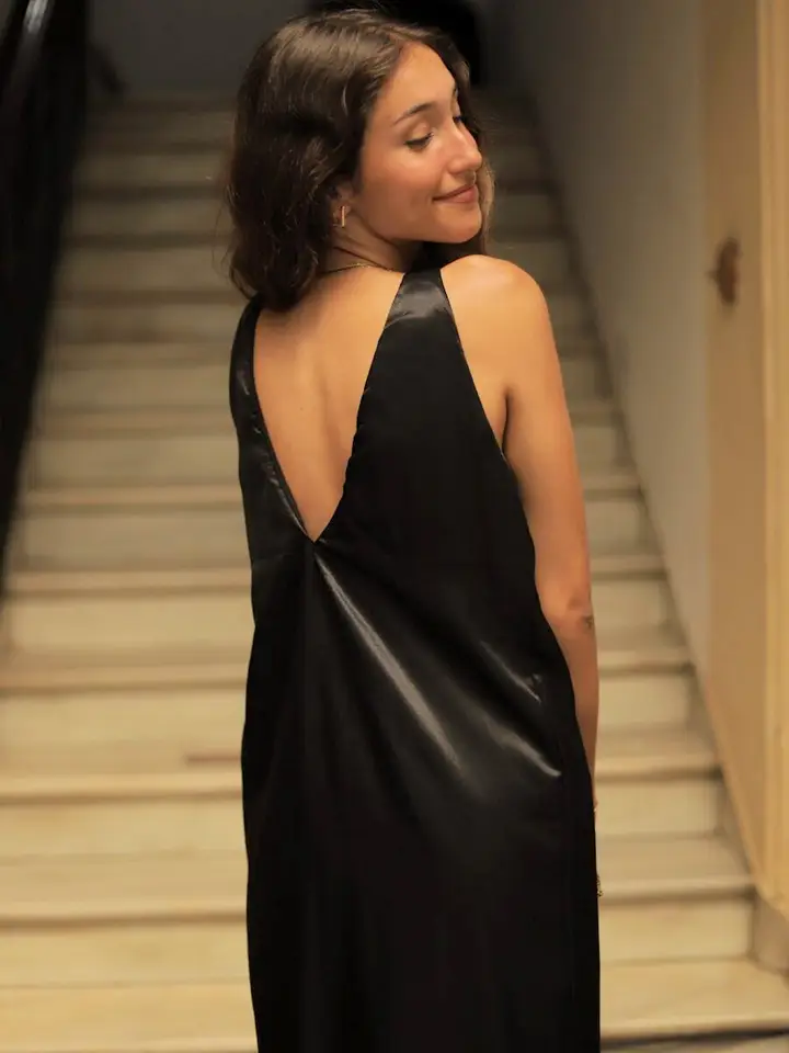 Vestido Negro Satén Motis con cinturón y abertura lateral. Diseño elegante y favorecedor, ideal para bodas, fiestas y eventos especiales.
