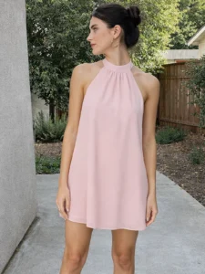 Vestido corto rosa perla en punto de seda con cuello halter y espalda baja. Diseño ligero y elegante para eventos y celebraciones.