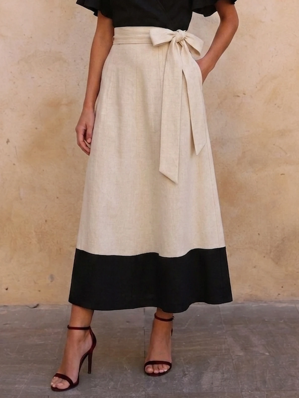Falda larga estampada con vuelo, cintura en V, lazo y bolsillo. Tonos beige, blanco y negro para looks de invitada elegantes, cómodos y con mucho movimiento