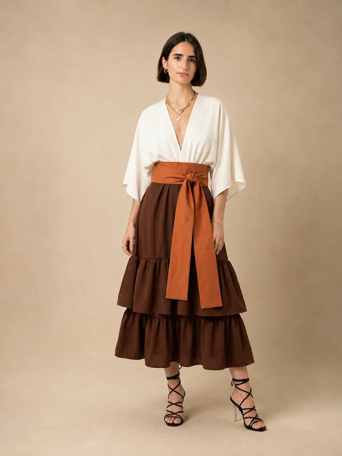 Vestido midi marrón Elmar con escote en pico, fajín a contraste y falda de dos volantes. Un diseño elegante y favorecedor para eventos.