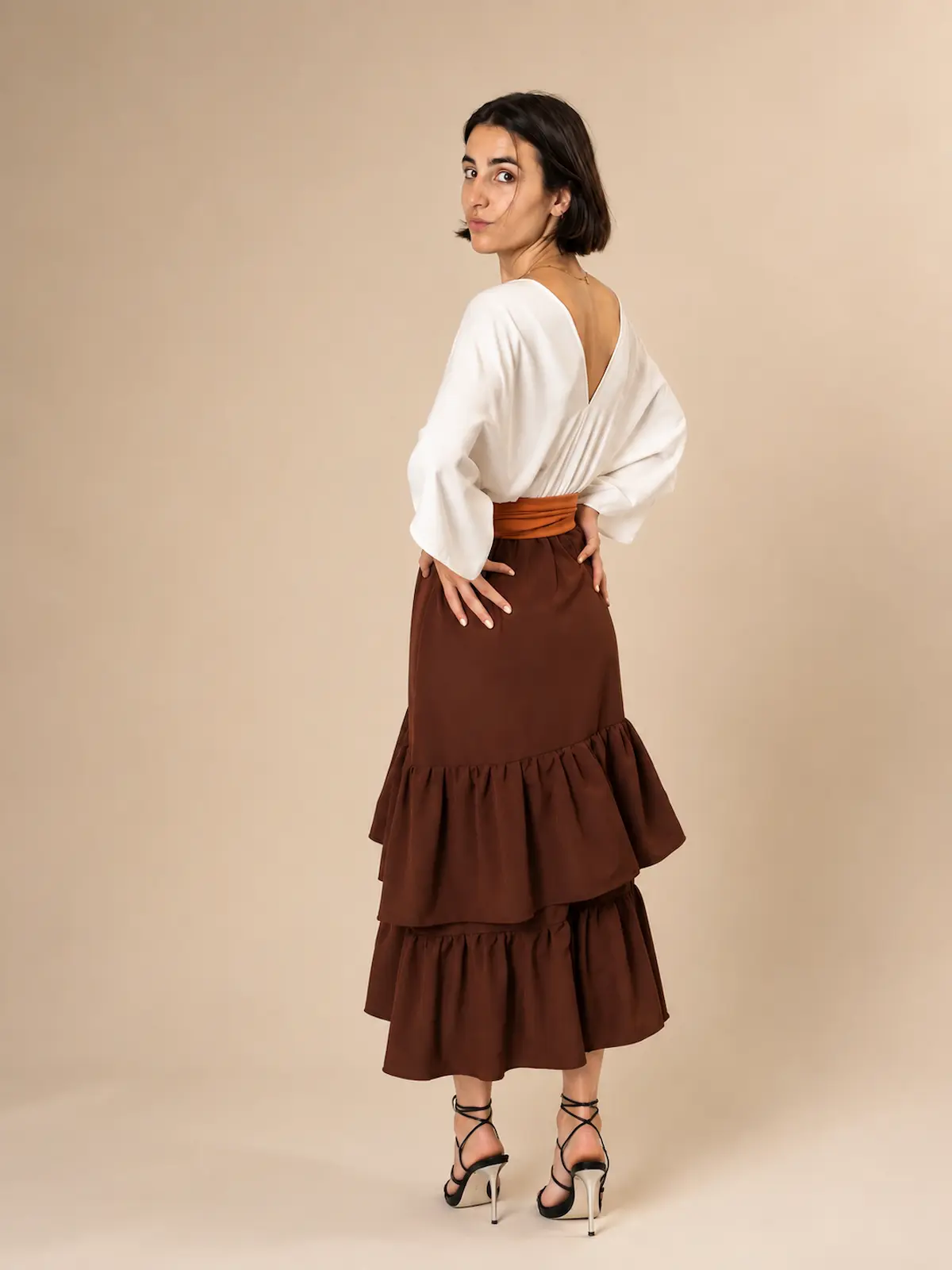 Vestido midi marrón Elmar con escote en pico, fajín a contraste y falda de dos volantes. Un diseño elegante y favorecedor para eventos.