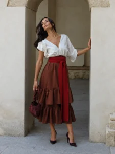 Vestido midi marrón Elmar con escote en pico, fajín a contraste y falda de dos volantes. Un diseño elegante y favorecedor para eventos.