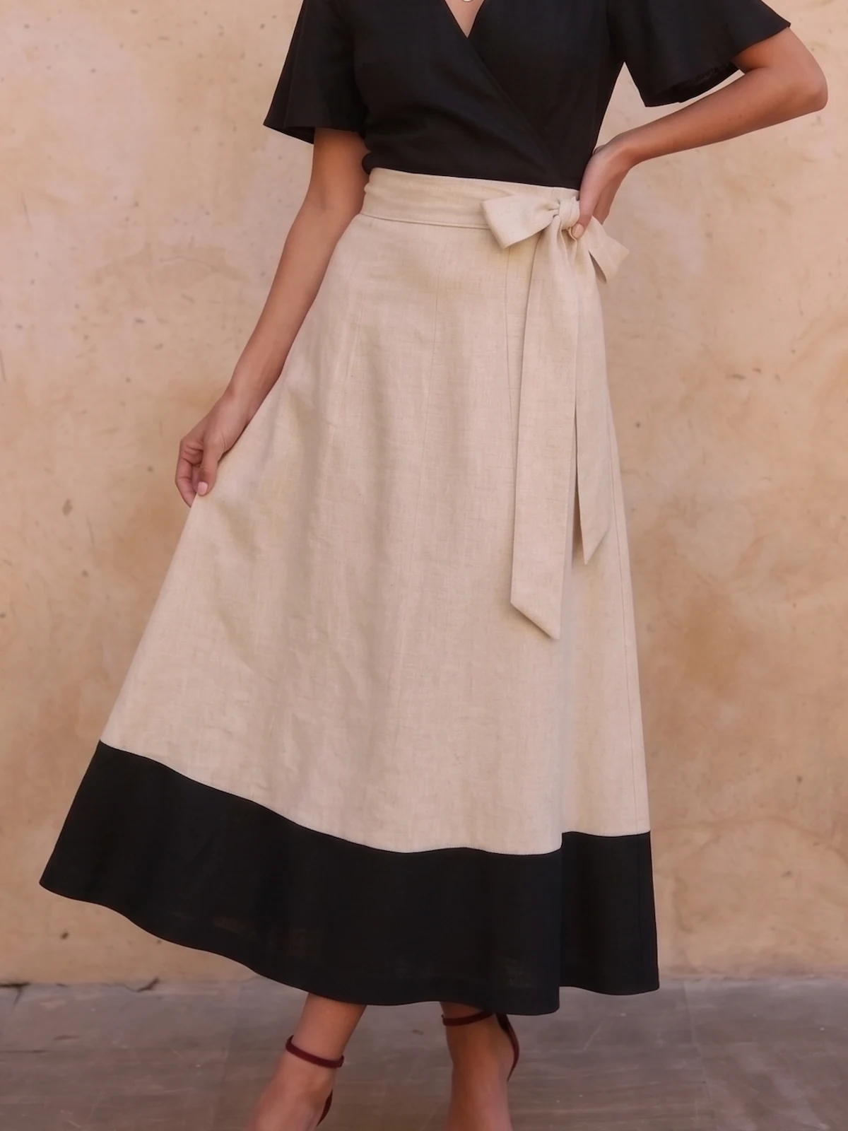 Falda larga estampada con vuelo, cintura en V, lazo y bolsillo. Tonos beige, blanco y negro para looks de invitada elegantes, cómodos y con mucho movimiento