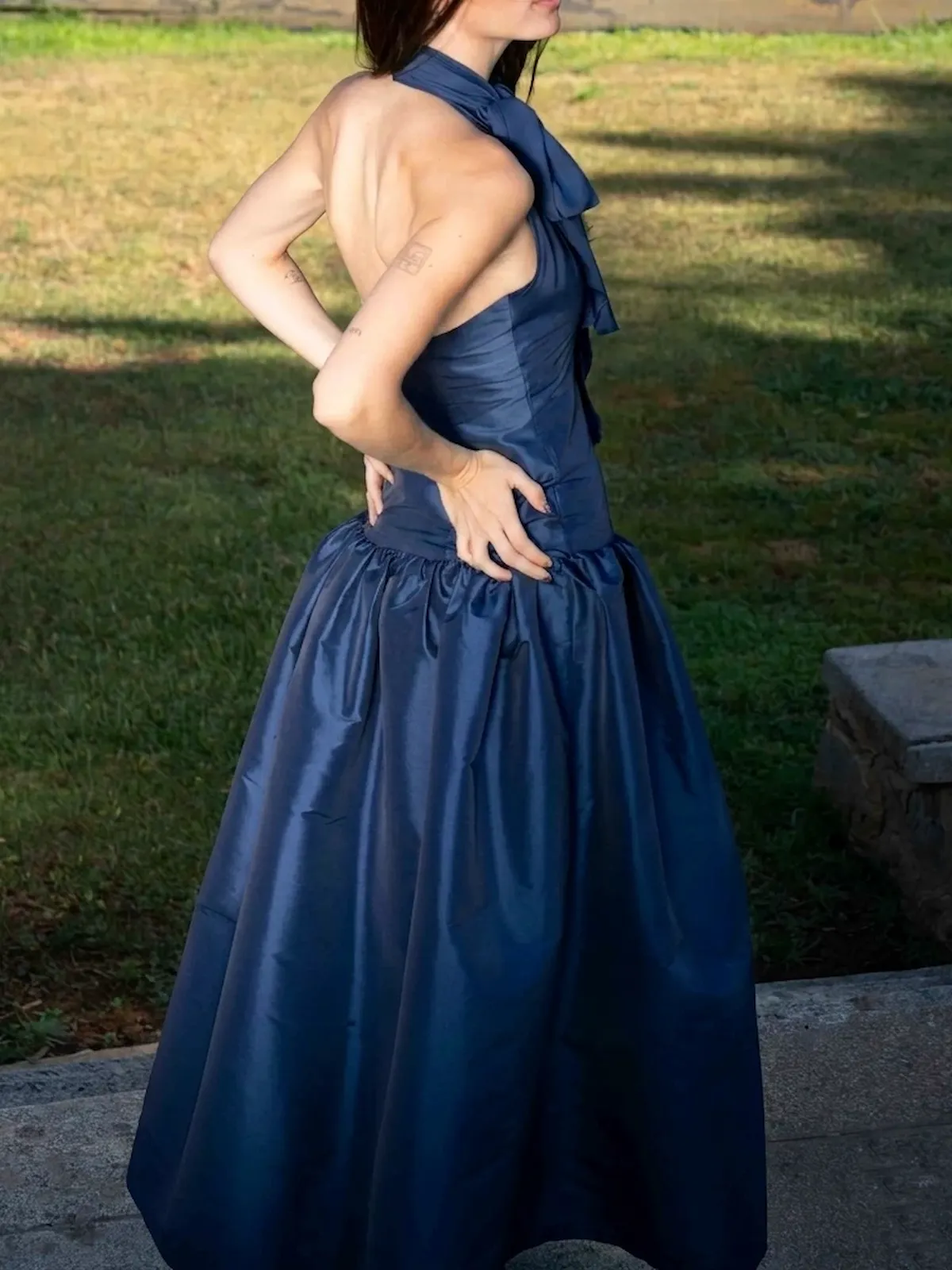 Vestido largo azul marino en tafetán con cuello halter y lazada. Su cuerpo estilizado y su amplia falda con volumen crean una silueta elegante y sofisticada, perfecta para bodas, graduaciones y eventos especiales.