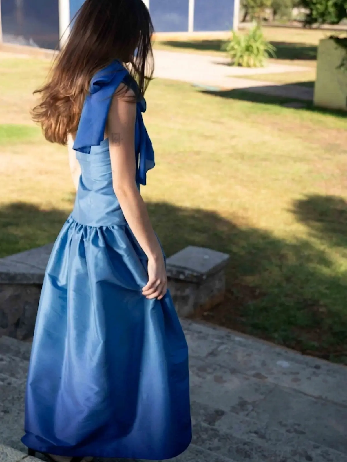 Vestido largo azul en tafetán con cuello halter, lazada y espalda descubierta. Su cuerpo estilizado y su amplia falda con volumen crean una silueta elegante y sofisticada para bodas, graduaciones y eventos especiales.