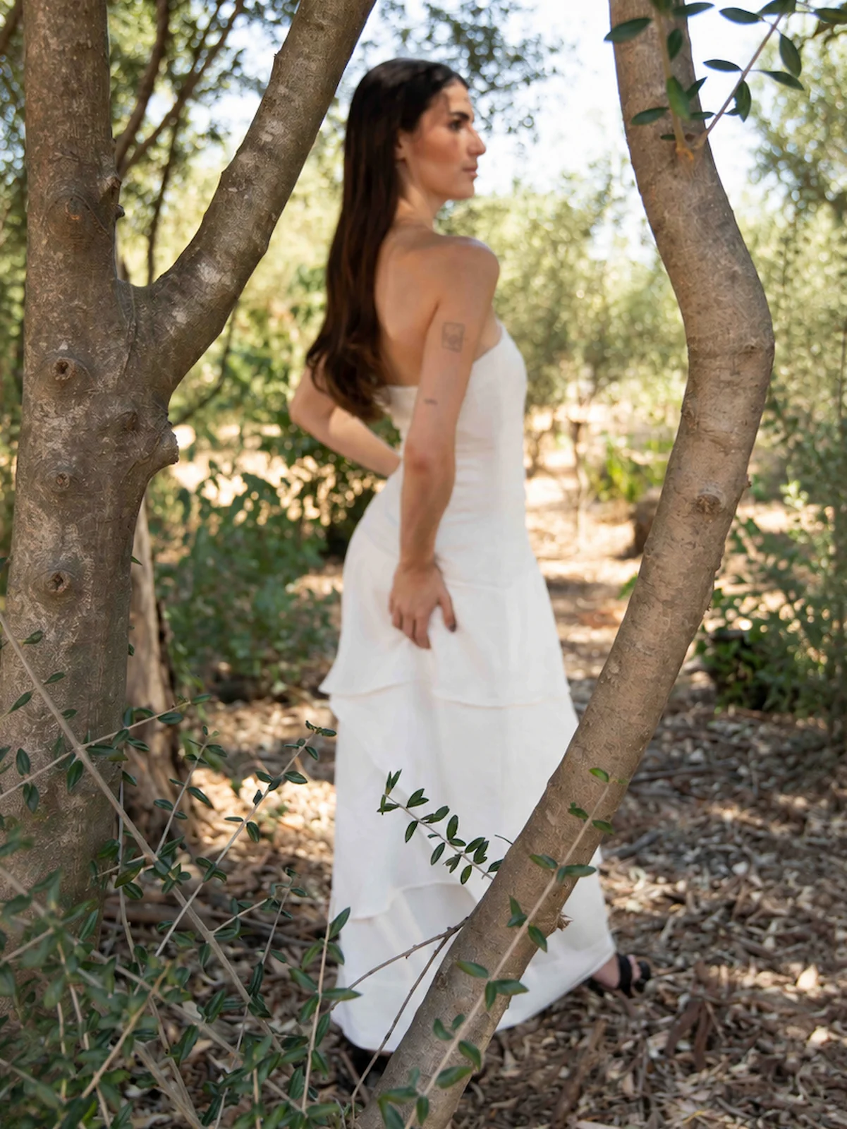 Vestido largo blanco Eleven con escote palabra de honor, cuerpo entallado y falda de capas asimétricas. Elegante, ligero y femenino.
